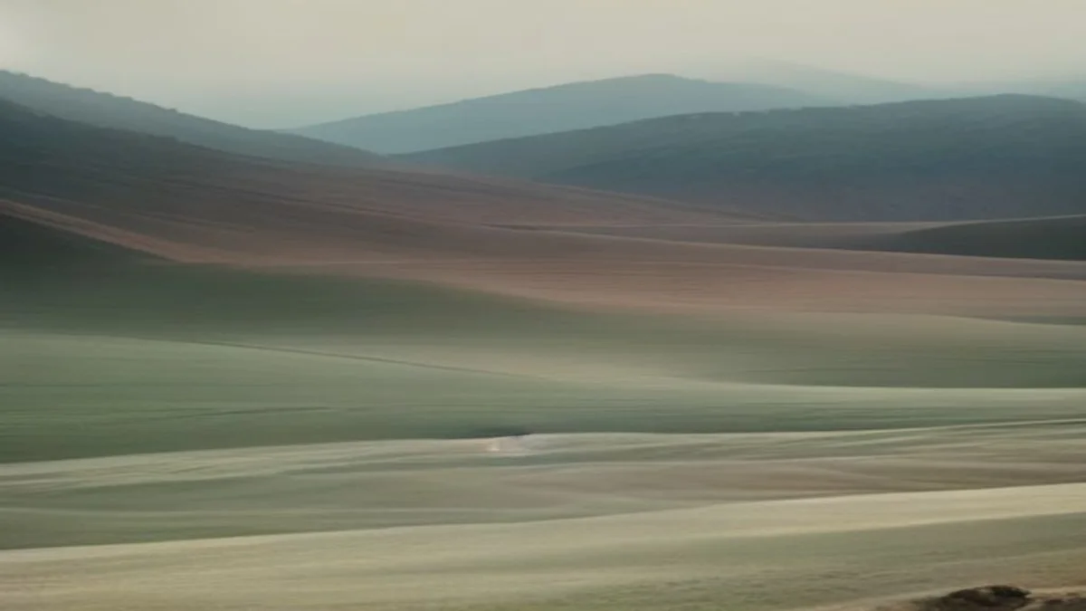 soft mineral landscape with terraced earth and quiet machinery in dawn haze
